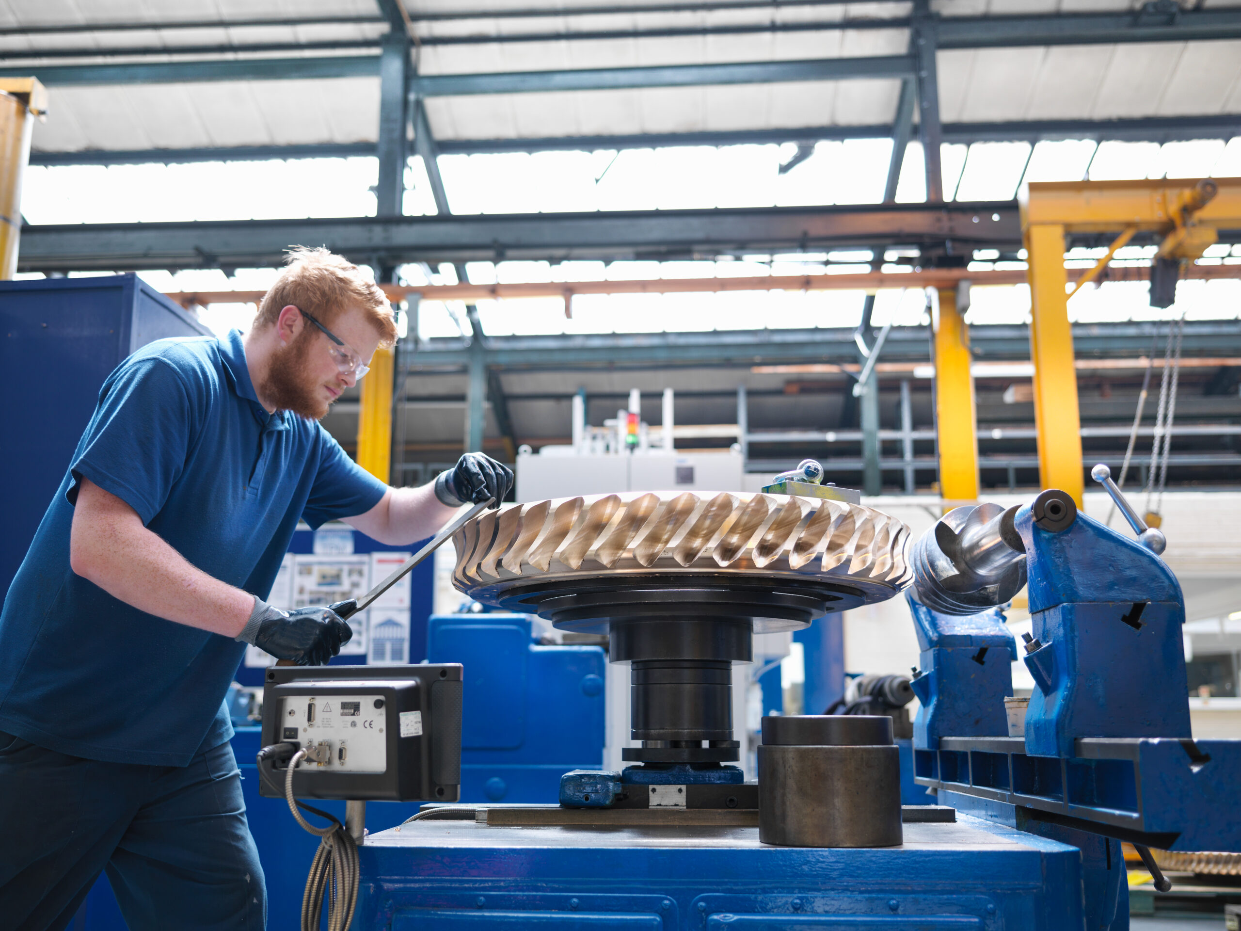 Engineer finishing bronze gear wheel in engineering factory